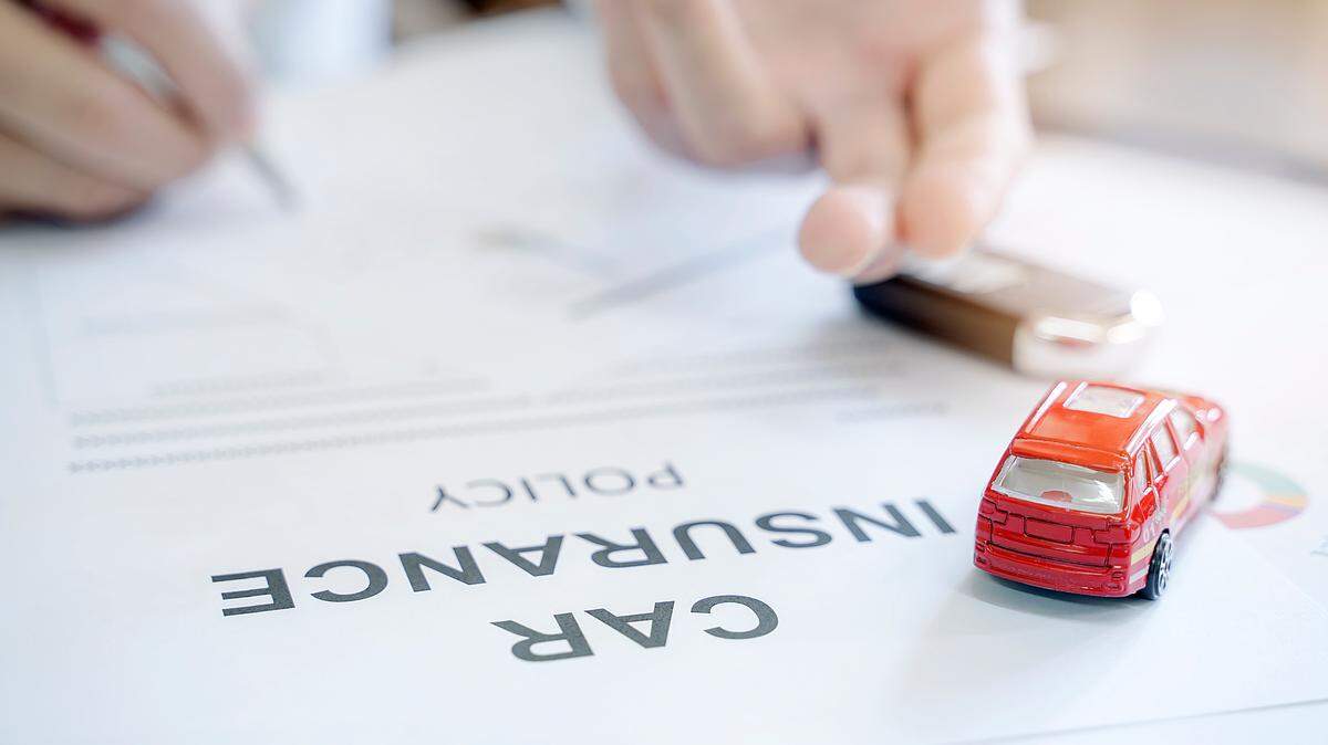 Car insurance policy with red car toy and blur image of man hand for vehicle insurance policy concept.