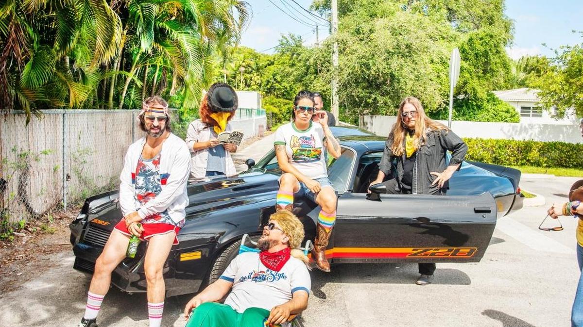 Mad Cat Live! get in a peaceful easy feeling, Miami style, in recreating the Eagles’ ethos. (L-R): Darren Bruck, Erik Fabregat (foreground), Fritz Dorigo (in eagle mascot head), Nabedi Osorio on the car, and Jim Camacho next to the side door.