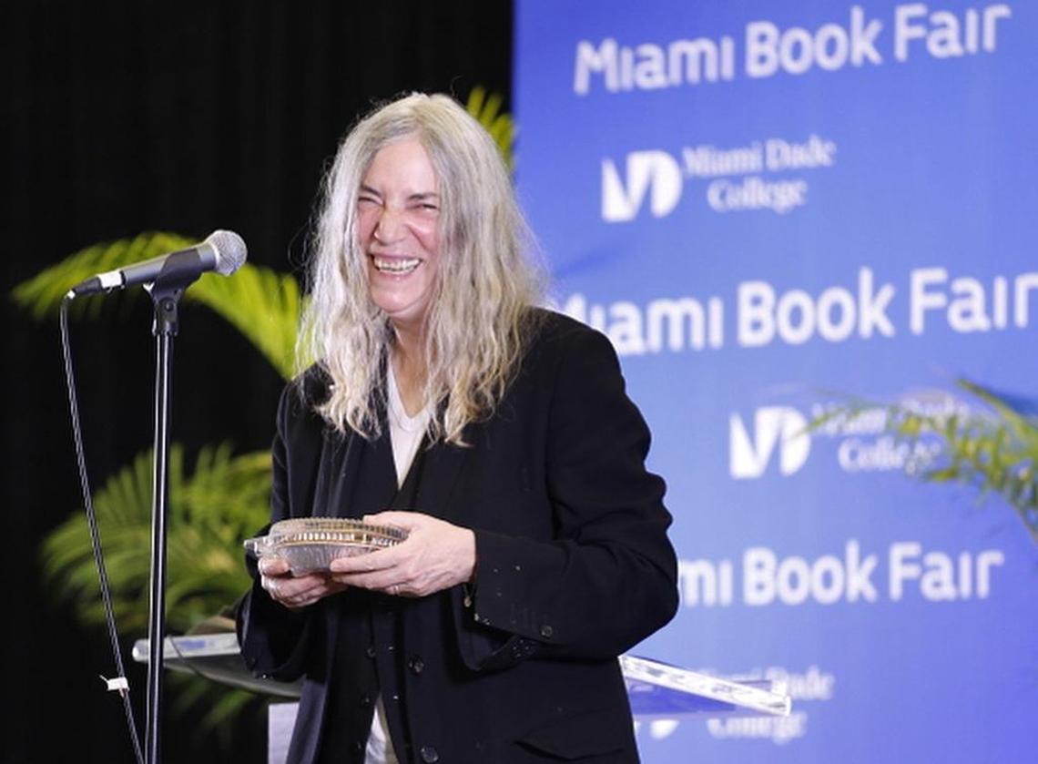 Patti Smith, smiling here after receiving a cherry pie from Miami-based journalist John Hood at a previous Miami Book Fair, returns this year, too.