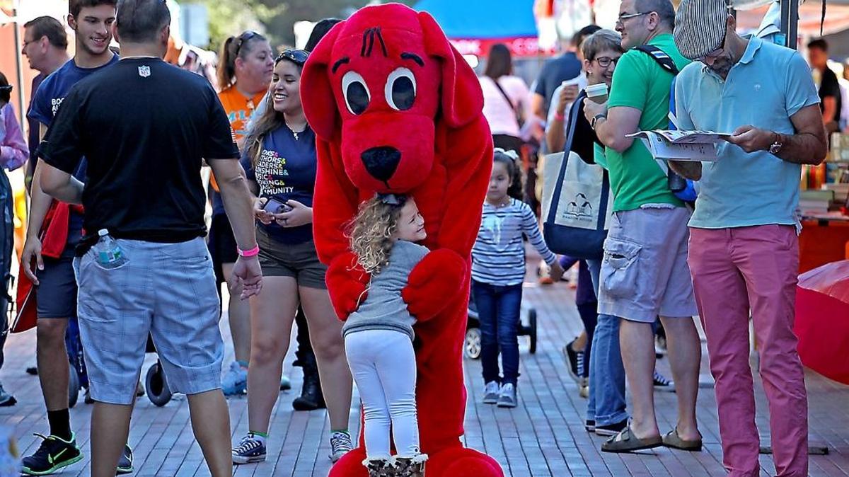 Lily Lampert, 4, of Miami gets a hug from Clifford the Big Red Dog during last day of the Miami Book Fair on Sunday, Nov. 20, 2016.