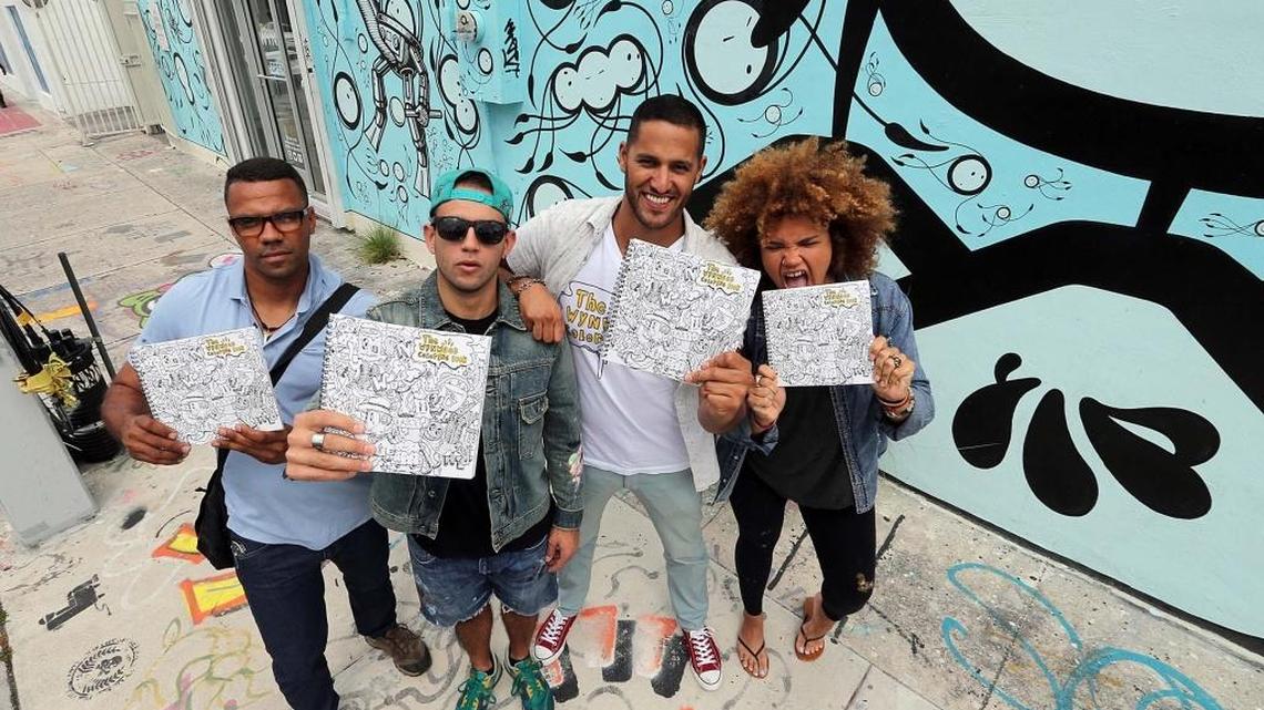 From left, artists Will Rodriguez, Gabriel ‘GG’ Gimenez, Diego Orlandini and Jenny Perez display the ‘Wynwood Coloring Book,’ created by Orlandini, which includes many of the artists’ wall murals in Wynwood for people to color.
