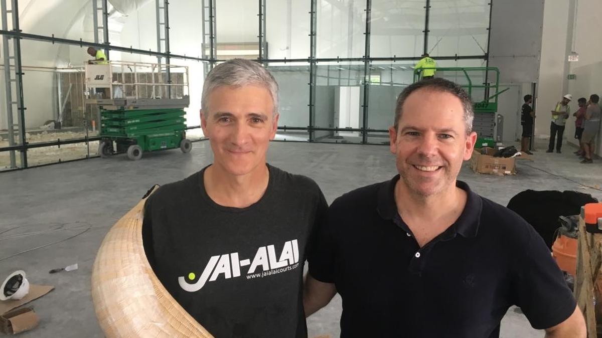 Gonzalo Vivanco, left, and Iñigo Calzacorta own a company that builds jai-alai courts. They hustled up to build one in Florida City, but the glass wall, shown behind them, broke four times.
