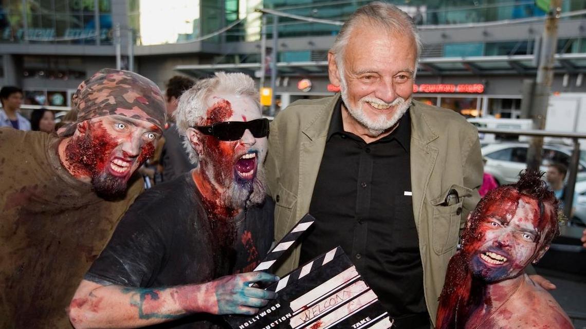 FILE - In this Sept. 12, 2009, file photo, director George Romero poses with some fans dressed as zombies after accepting a special award during the Toronto International Film Festival in Toronto. Romero, whose classic "Night of the Living Dead" and other horror films turned zombie movies into social commentaries and who saw his flesh-devouring undead spawn countless imitators, remakes and homages, has died. He was 77. Romero died Sunday, July 16, 2017, following a battle with lung cancer, said his family in a statement provided by his manager Chris Roe.