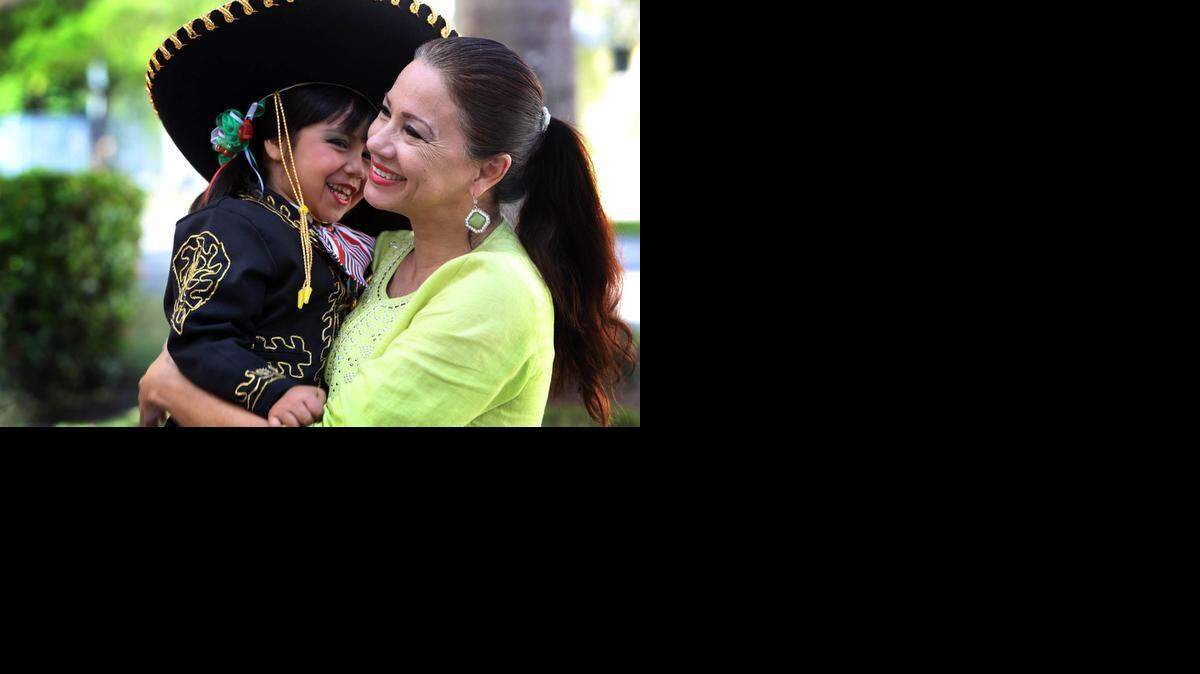 
Maria Garza of the Mexican-American Council and 4-year-old old Delayla Irene Gasca in her Mariachi costume share a light moment in front of the offices of the Mexican American Council in Homestead.
