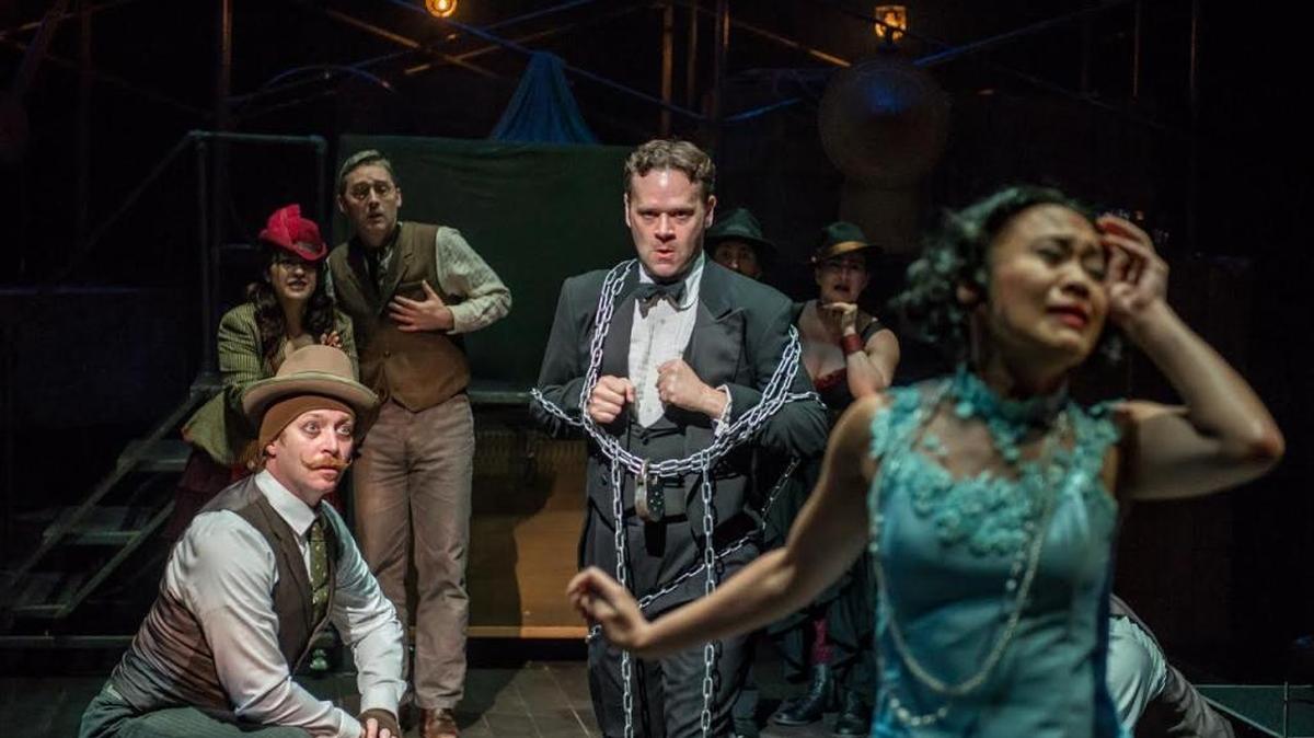 Dennis Watkins prepares to escape his chains as Emjoy Gavino reacts in the House Theatre’s “Death & Harry Houdini” at the Arsht Center.