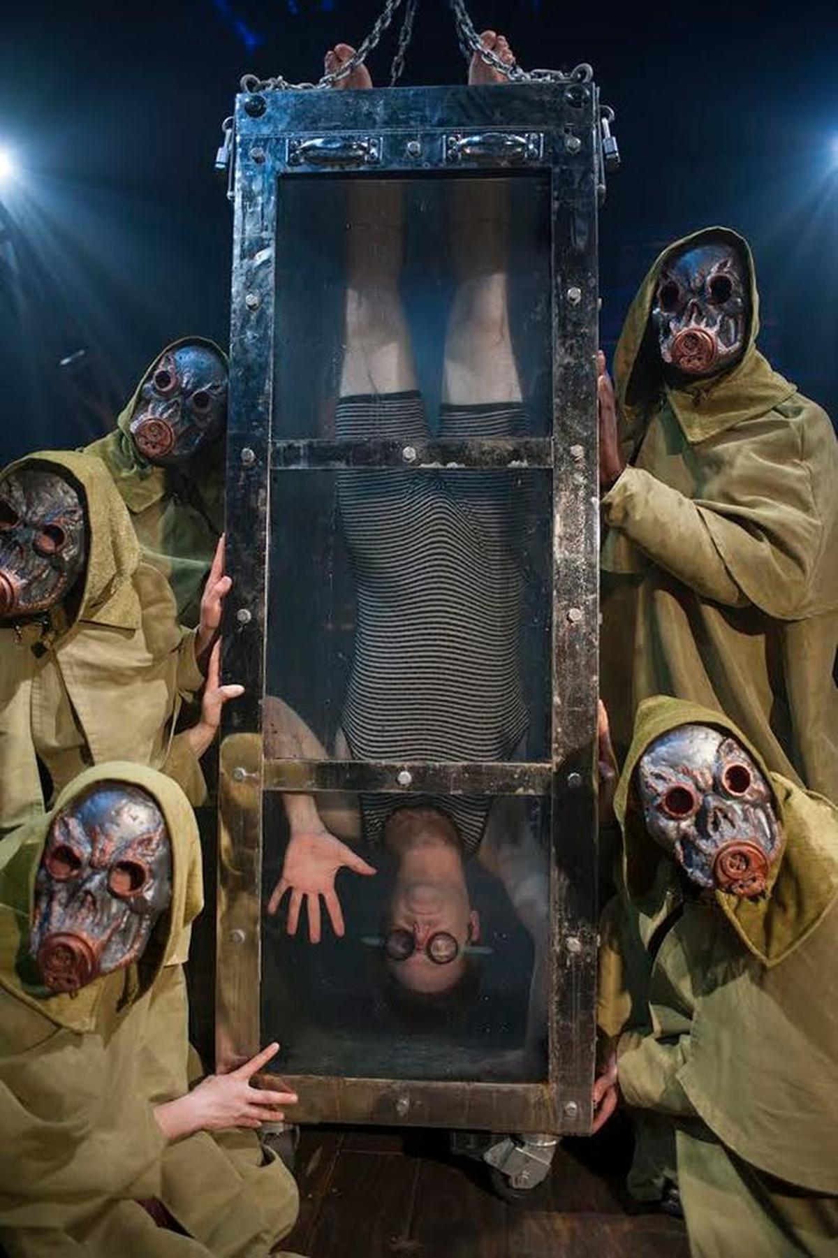 Dennis Watkins dangles upside down in the Water Torture Cell in “Death & Harry Houdini” at the Arsht Center.