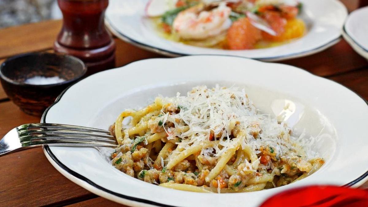 Housemade bucatini with rabbit bolognese and porcini fondue as well as wood-roasted Florida shrimp (background) are among Michael’s Genuine Fine Dining Miami Spice options.