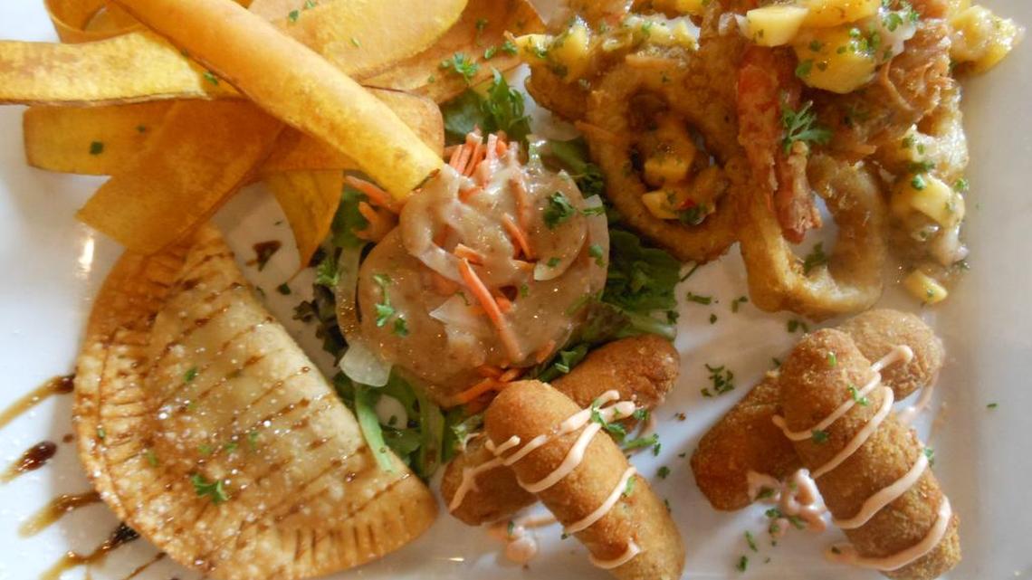 A selection of appetizers: clockwise from the back, mariquitas (plantain chips), fried calamari and coconut shrimp, croquettes and a ground beef empanada dusted in powdered sugar with balsamic vinegar at Bella Cuba, Miami Beach.