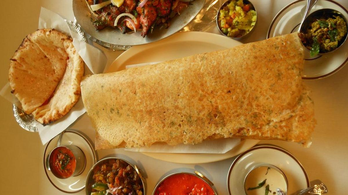 Rice and dal batter dosa, center, with chutneys, naan bread and tandoori chicken at 5th Element Indian Grill.