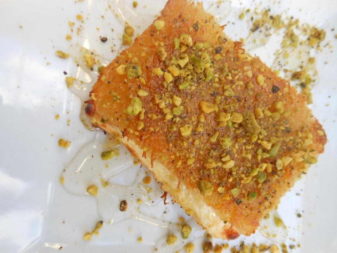 Kenafi with slightly sweet cheese between shredded phyllo soaked in orange blossom syrup with crushed pistachios.