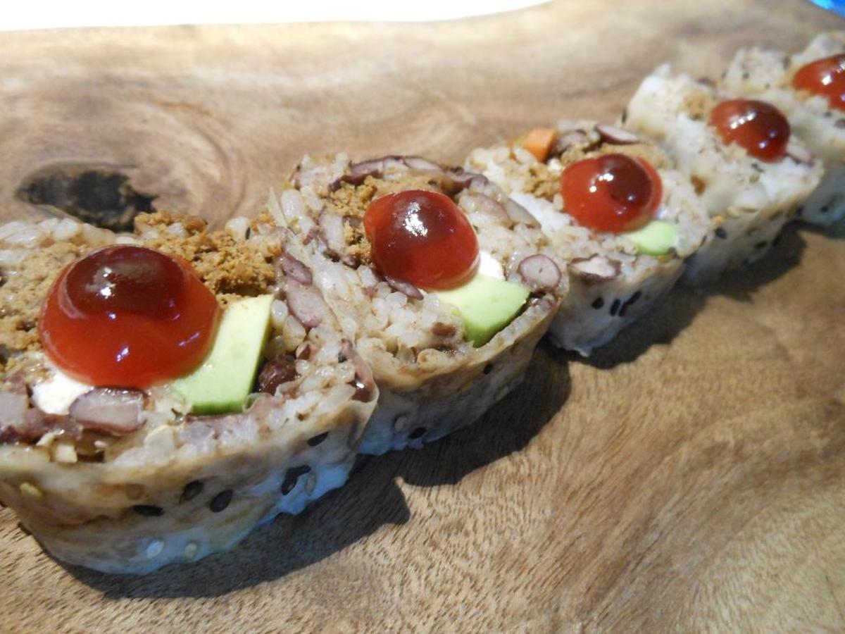 The American roll with rice and black beans, flaked meatloaf, cream cheese and avocado, rolled in sesame seed soy paper and topped with ketchup and BBQ sauce.