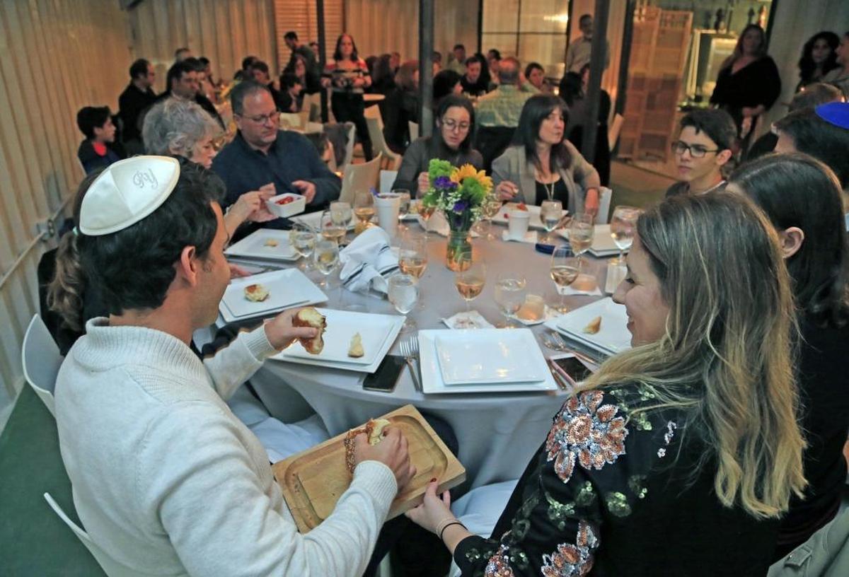 Guests break bread during Shabbat dinner at Wynwood Yard on Saturday, Jan. 20, 2018. Several restaurants in Miami have started to offer communal dinners for what traditionally has been a holy and traditional Jewish meal eaten with family or after temple to mark the start of the Sabbath on Friday night. The dinners are not kosher. Instead, these shabbat meals are about community and bonding over a meal.