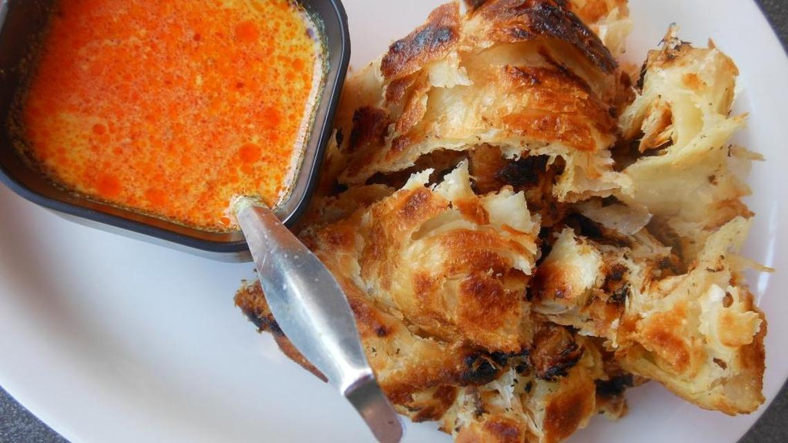 Strips of flaky grilled roti canai with yellow coconut curry for dipping at East Thai Noodle House.