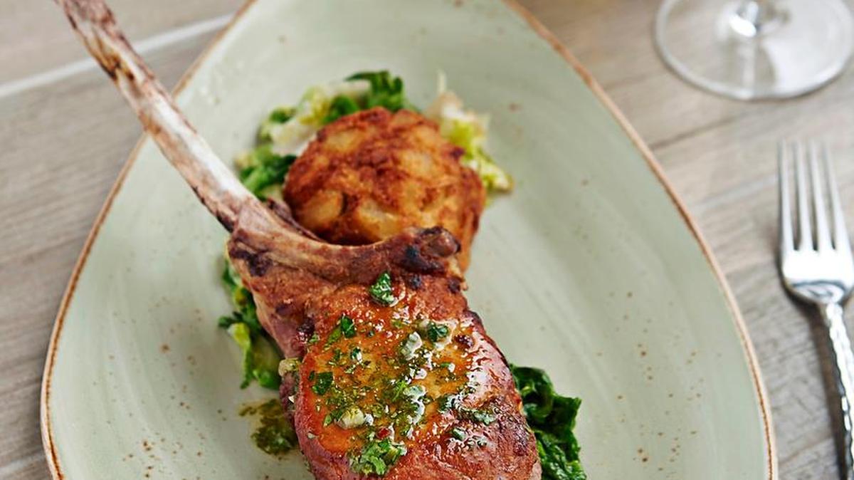 Pork tomahawk chop at Zest with yuca cakes and sauteed escarole.