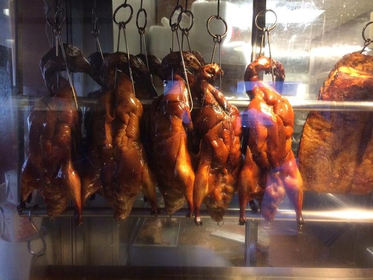 Barbecued ducks hang in a hot box near the register.