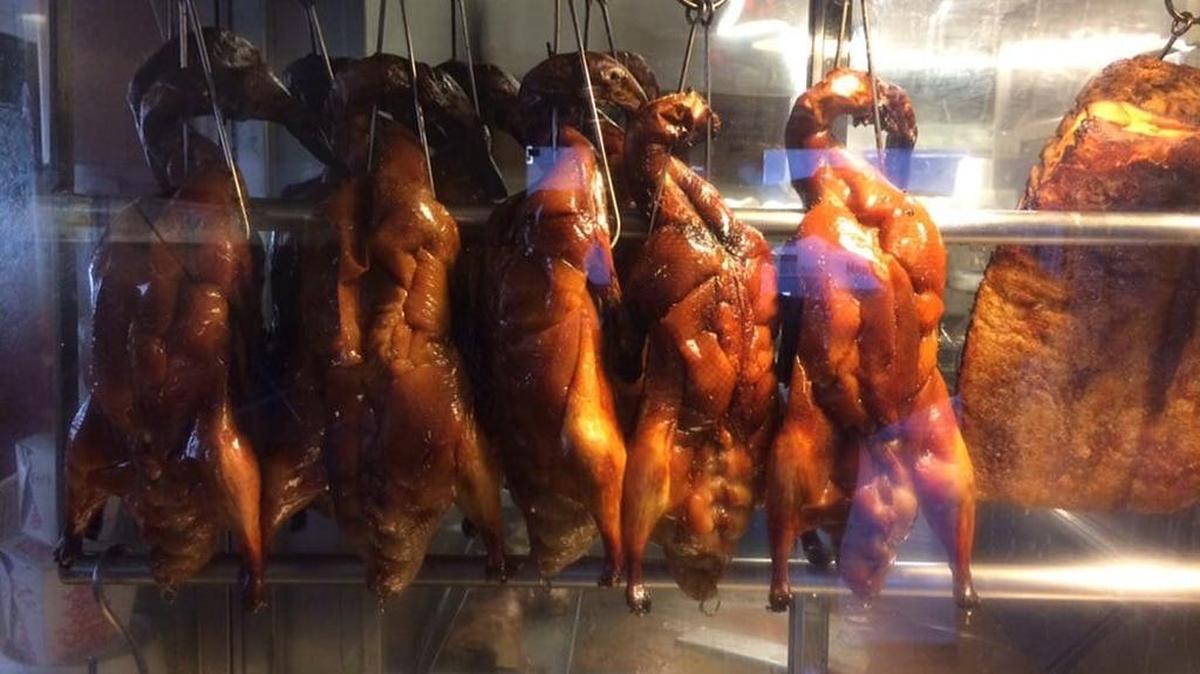 Barbecued ducks hang in a hot box near the register.