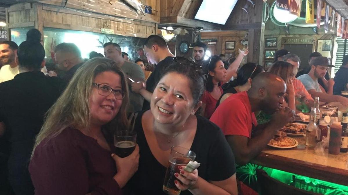 Sisters Cynthia (left) and Sandra Jamarillo took a break from hurricane recovery to have a cold beer and a warm food at a local Flanigan’s.
