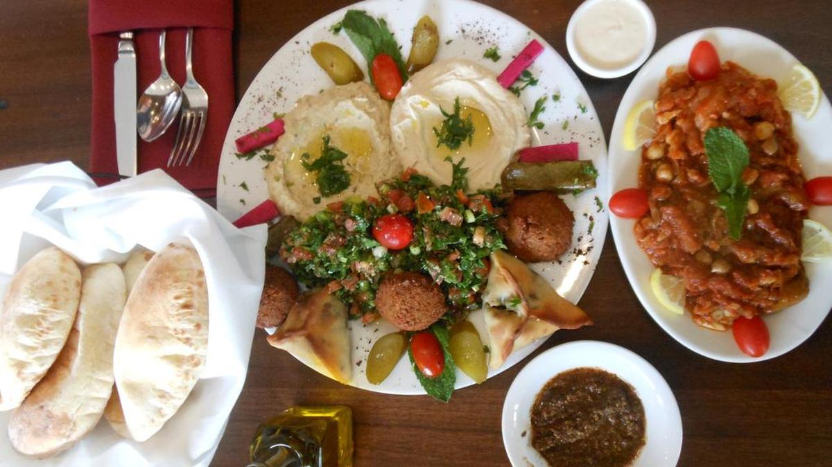 Mezza platter with hummus, falafel and rice stuffed grape leaves with a side of lamb and bean stew and pita bread at Mijana Lebanese restaurant, Gulfstream Park.