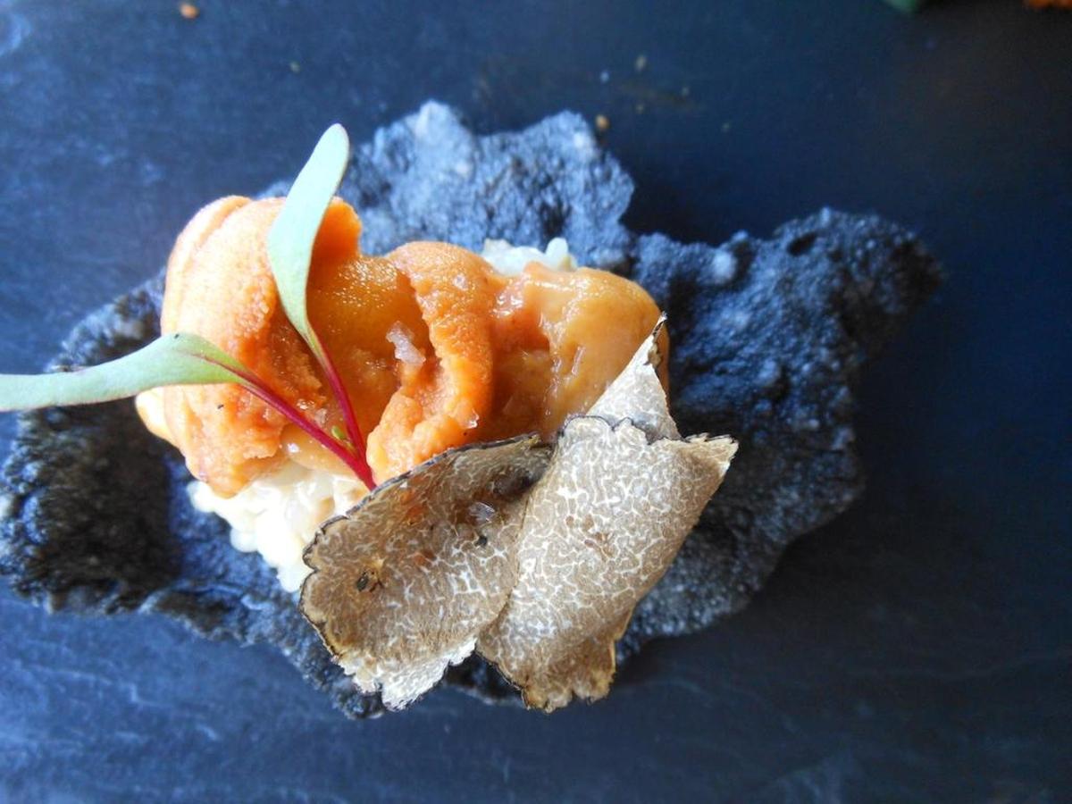 Squid ink rice cracker topped with sea urchin and shaved truffle at Tanuki.