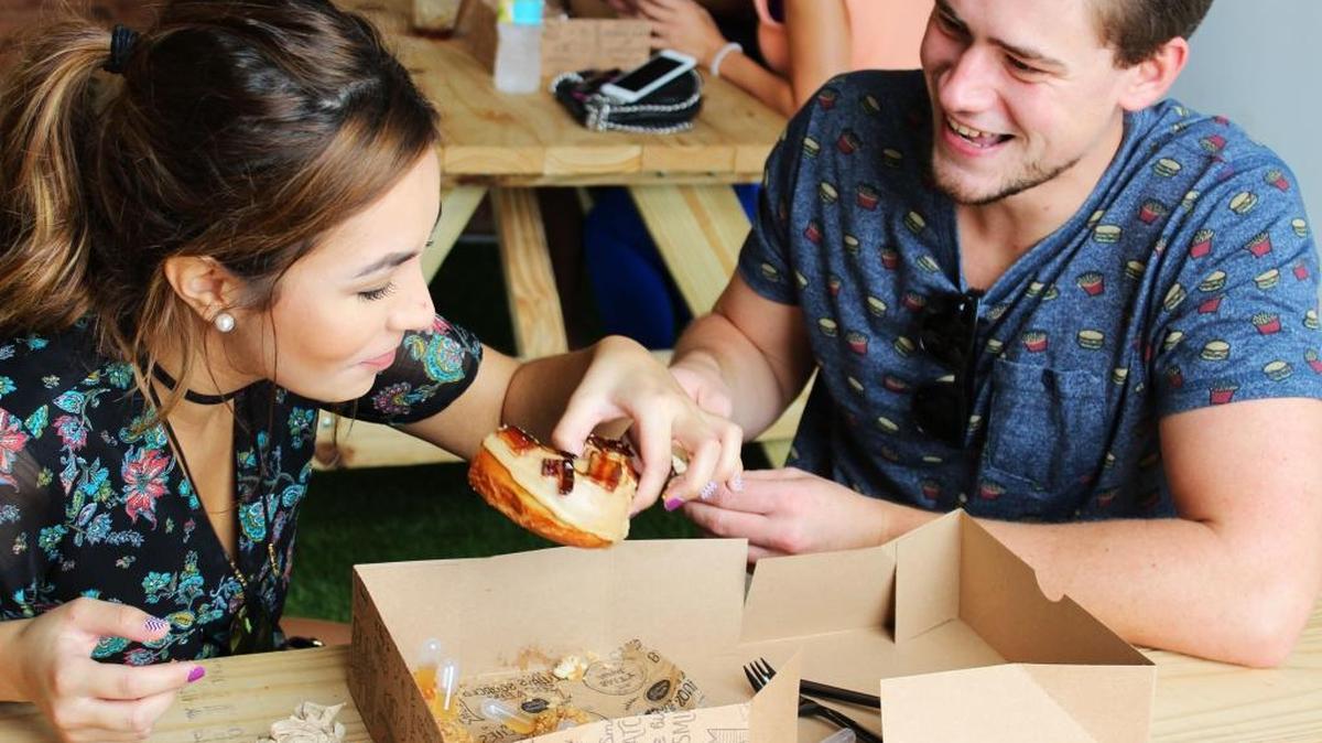 Chloe Lecusay enjoys a maple bacon donut as she talks to Joey Bodovetz.
