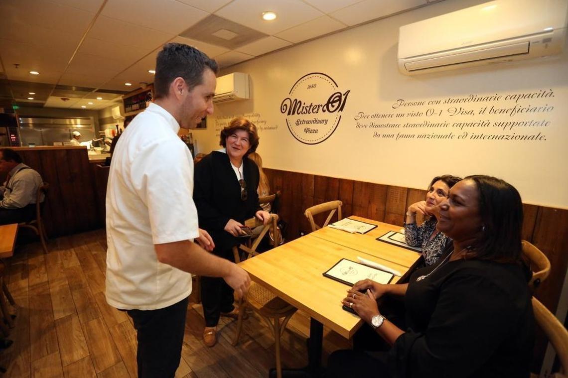 Mister 01 chef and co-owner, Renato Viola, wishes customer Carla Dixon, far right, a happy birthday as she and her friends visit his restaurant in Miami Beach on Tuesday, March 6, 2018. Viola was an award-winning pizza chef in Italy who gained entry into the United States under an O-1 visa for temporary workers, as an ‘individual who possesses extraordinary ability.’