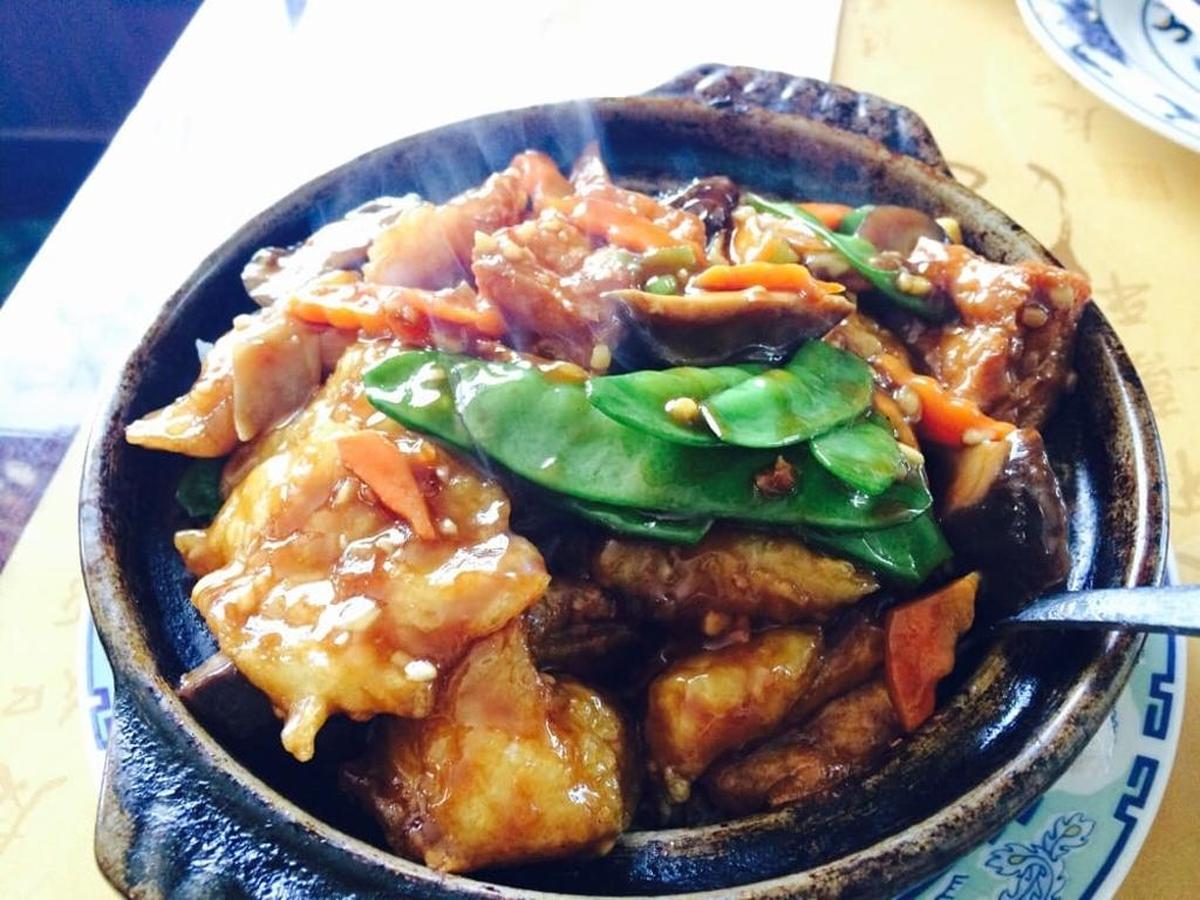 Breaded and fried grouper and tofu with snow peas served in a cast iron hot potat King Palace.