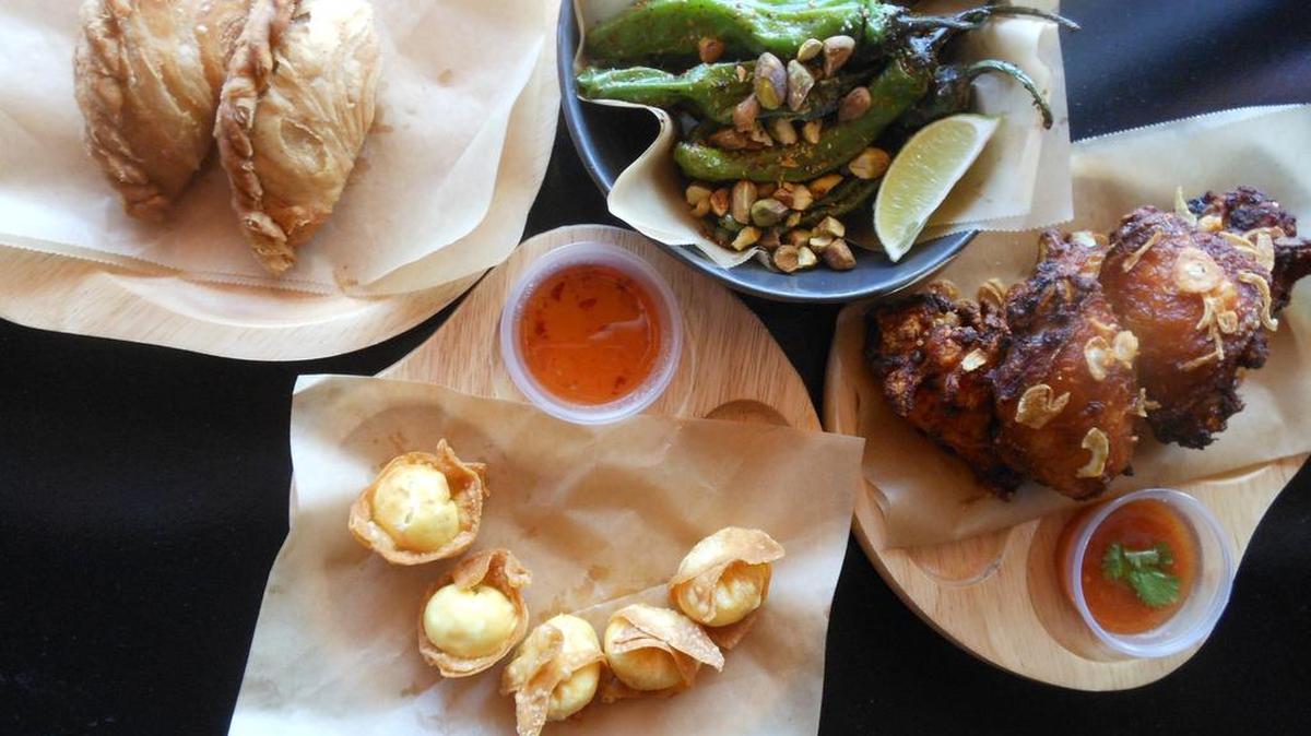 Chicken curry puffs, shishito chiles sautéed with crushed pistachios, Japanese tatsua-age (deep fried chicken nuggets with crispy shallots) and crab rangoon at Kin Asian Street Food, Pompano Beach.