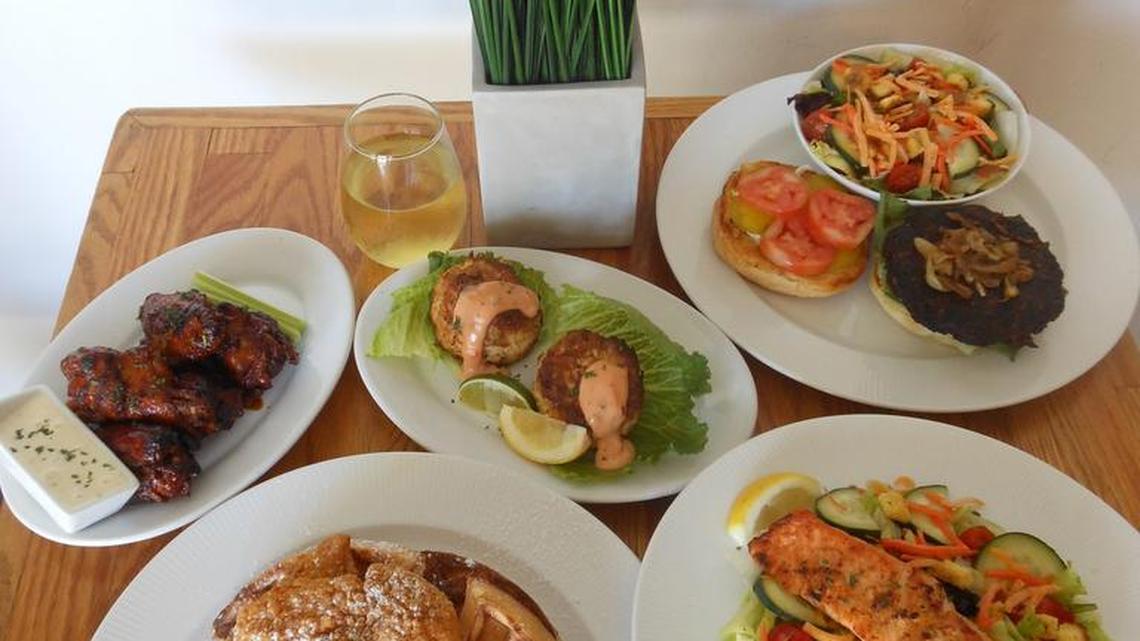 Chicken and waffles, grilled salmon on salad, veggie burger, chicken drumettes and seafood cakes served at Lil Greenhouse Grill in Overtown.