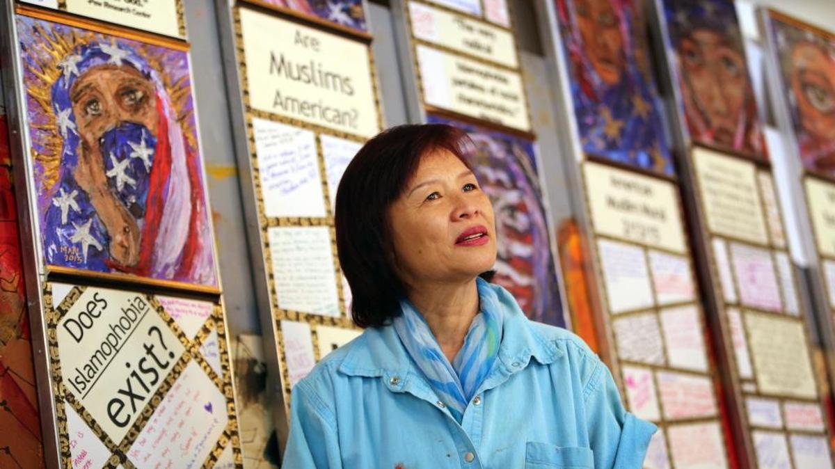 Miami-based artist Huong stands in front of a 100-foot by 8-foot tall mural inspired by the plight of American Muslims. The work is interactive, allowing those who view it the chance to write their opinions, discuss the issues among themselves or their feelings about the painting. It will be located on Washington Avenue in Miami Beach, open to the public starting Jan. 10.