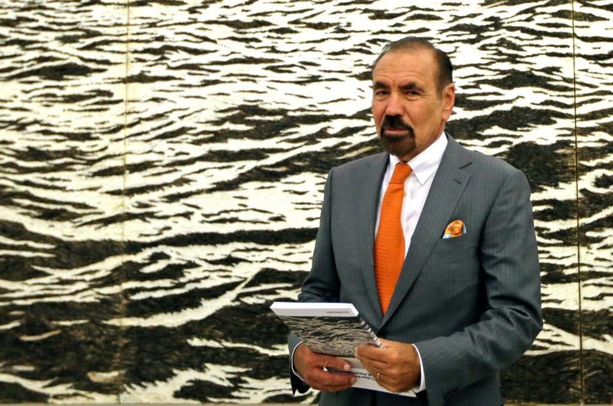 Jorge M. Pérez talks to guests and reporters at the Perez Art Museum Miami, in Miami, Fla. The artwork behind him, by Yoan Capote, incorporates more than a half-million fish hooks.