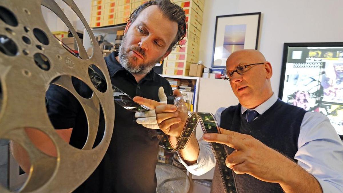 Obsolete Media Miami co-founders Barron Sherer and Kevin Arrow look at a 35mm reel of film in their Design District studio.