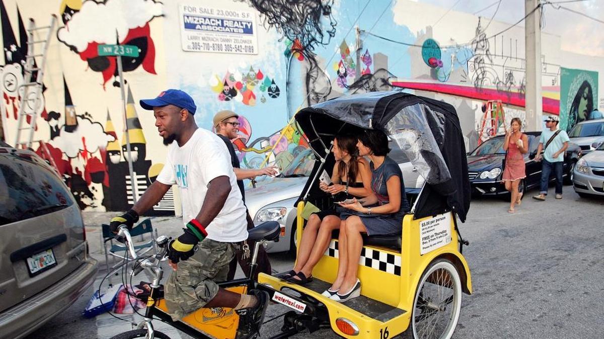 Art enthusiasts get around on a pedicab in Wynwood during Miami Art Week.