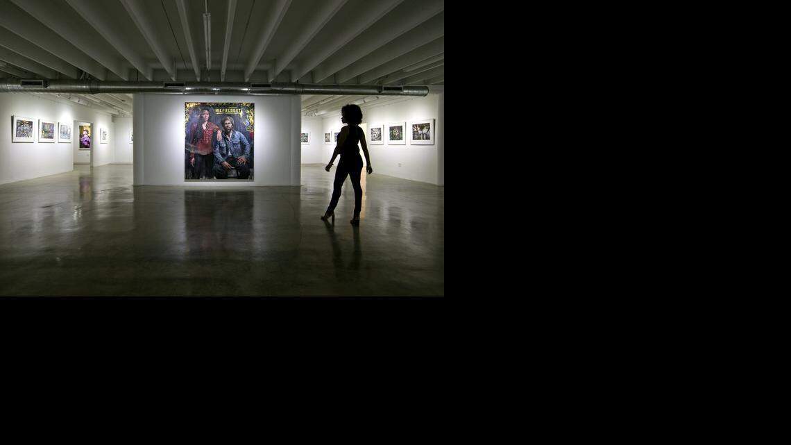 
Gallery owner Karla Ferguson views a work by artist Tim Okamura, titled “Represent,” at the Yeelen Gallery.
