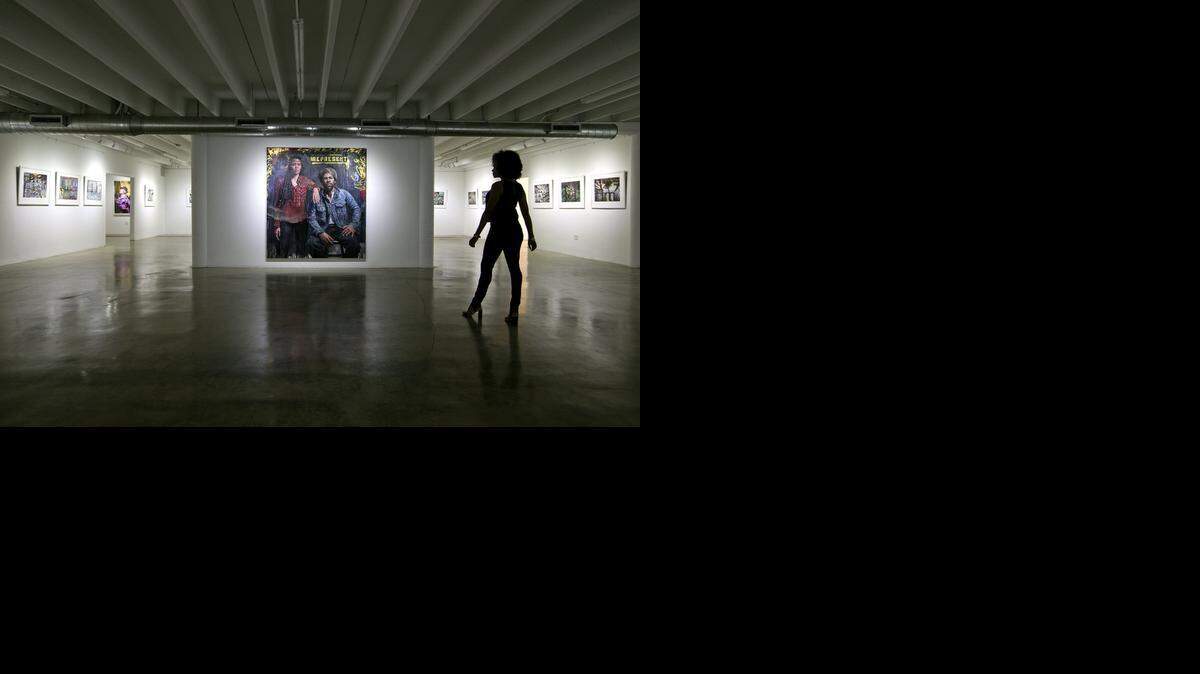 
Gallery owner Karla Ferguson views a work by artist Tim Okamura, titled “Represent,” at the Yeelen Gallery.
