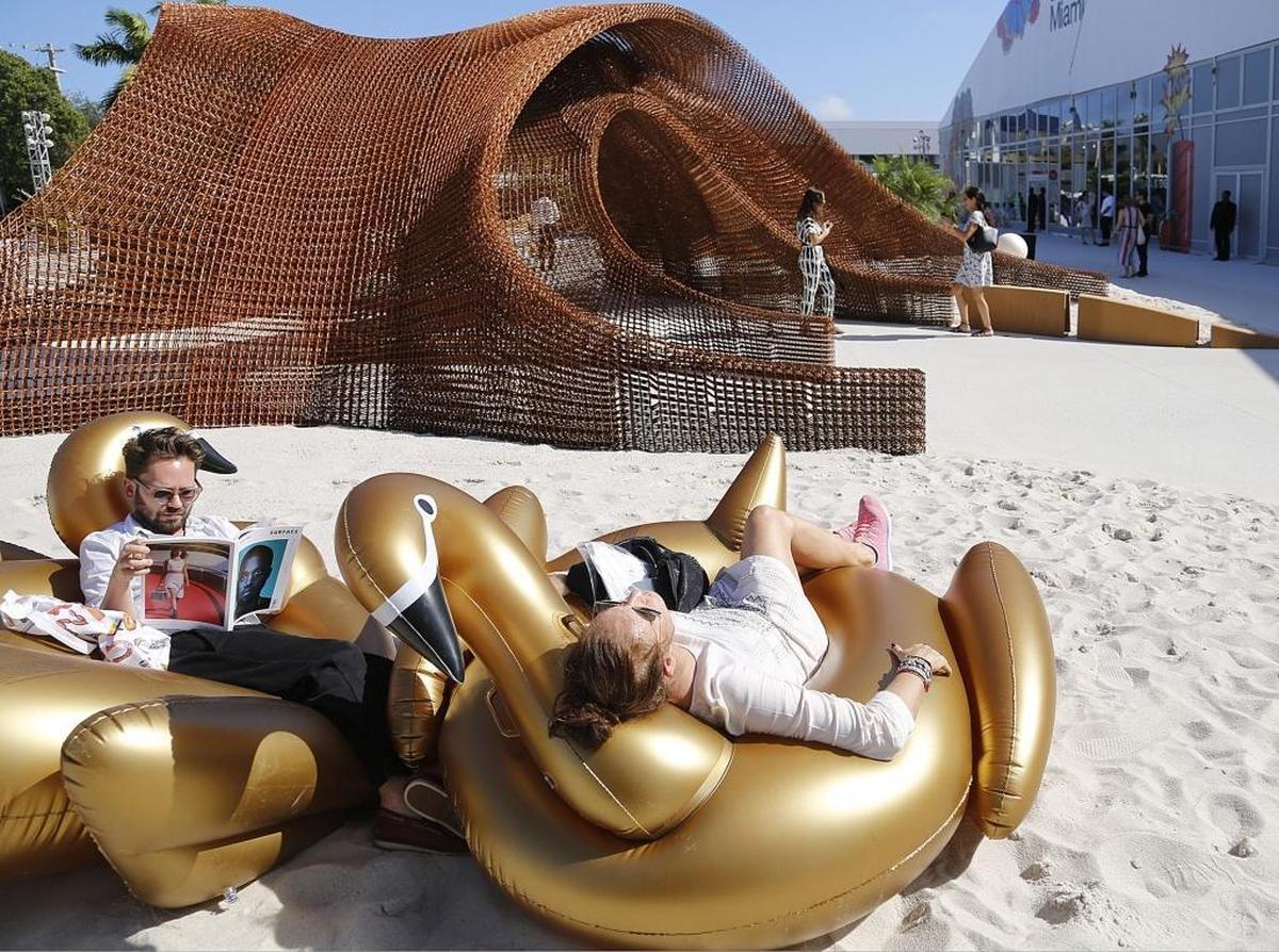 On Wednesday, Nov. 30, 2016, German visitors Susie Von den Stemmen, right, and Alexander Battle-Lachmann, left, took advantage of the weather outside the Design Miami pavilion on the first day of Art Basel Miami 2016.