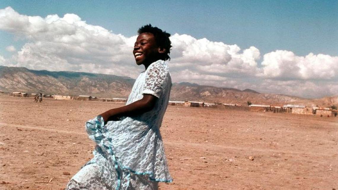 
Young girl dancing in her blue lace dress belies the sinister poverty and violence that reside in the dusty, dried-out streets of Rabato, a slum just outside Gonaives, Haiti. Rabato is a scene of regular political protest and is thus the target of numerous slaughters and attacks on its citizens. 1990
