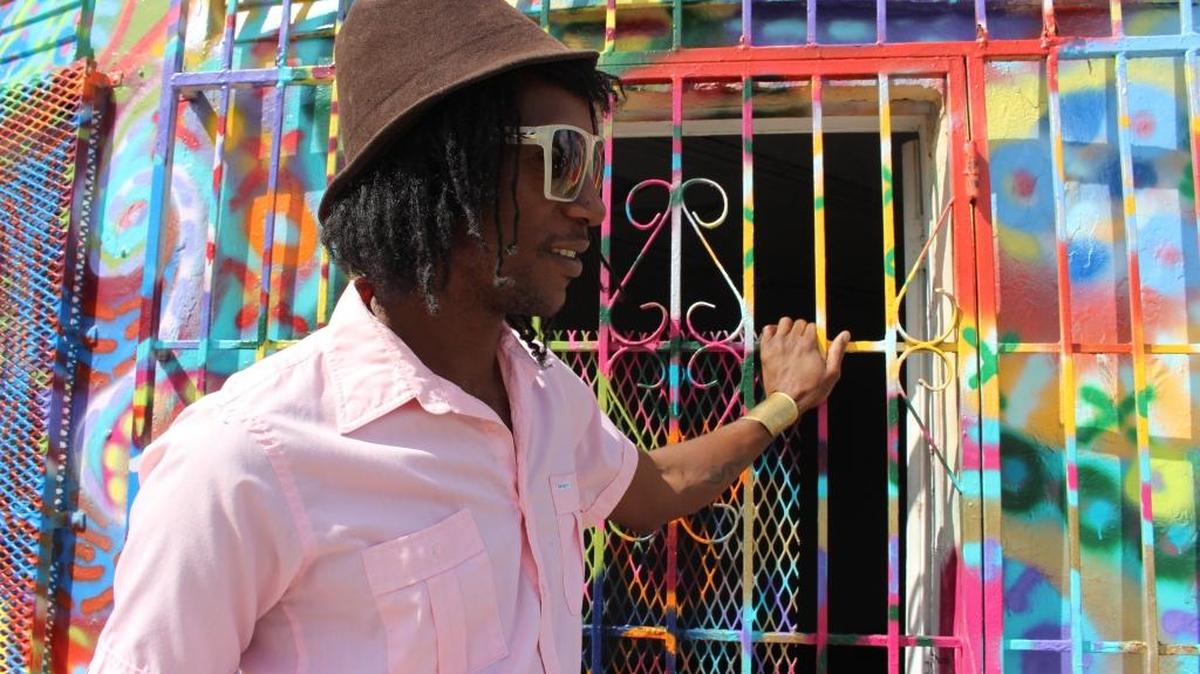 Artist Marcus Blake stands in front of a building he was commissioned to paint in Little Haiti.