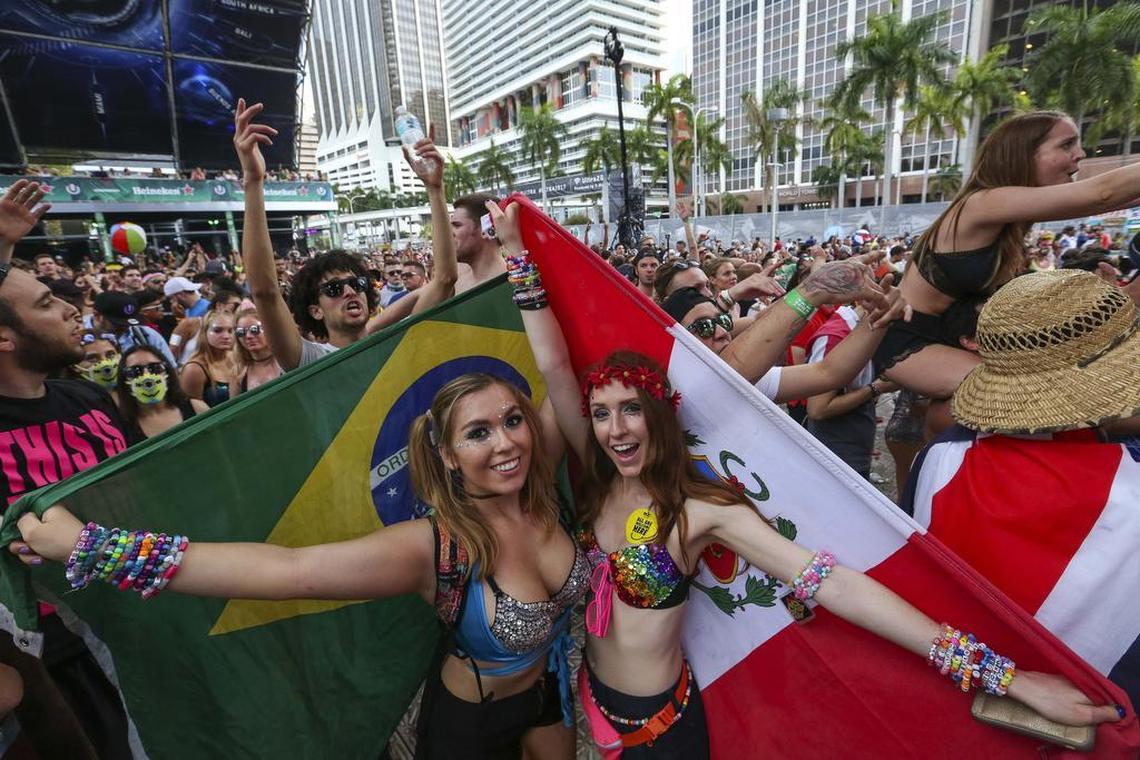 From left, Kiara Daniela Benac, 21, and Ale Ruttimann, 21, both from Miami, dance and wave flags from Brazil and Peru during the second day of Ultra Music Festival in downtown Miami on Saturday, March 25, 2017.