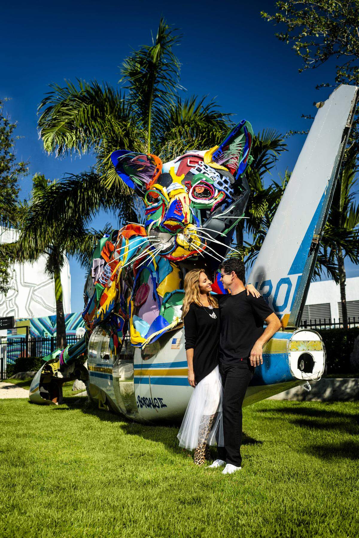 Jessica Goldman Srebnick and her husband, Scott Srebnick, share a moment in front of a sculptural work by artist Bordalo II. She wears a sweater and skirt by Morgane Le Fay New York, boots by Jimmy Choo, and jewelry by Flowen (fl-o-wen.com). Photograph by Nick Garcia. Styling by Elysze Held.