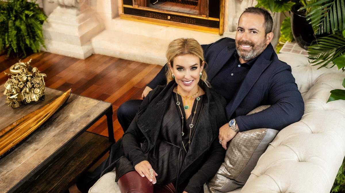 Dr. Brianna Varas and Manny Varas in their living room in Coral Gables' Cocoplum neighborhood. She wears a top, jacket and pants by Karolina Zmarlak; shoes by Zanotti; gold choker by Soledad Lowe; earrings, necklace and ring by Daniella Kronfle at Miami Design District. He's in a sweater by Brunello Cucinelli; jacket and pants by Kiton, all from Saks Fifth Avenue at Brickell City Centre. Photograph by Nick Garcia. Styling by Elysze Held. Hair and makeup by Pasquale Caselle and Yady Ochoa. Plants by Roses et Pivoines. Coffee table sculpture by Keith Richard Clougherty from Nisi B Home Design Gallery.