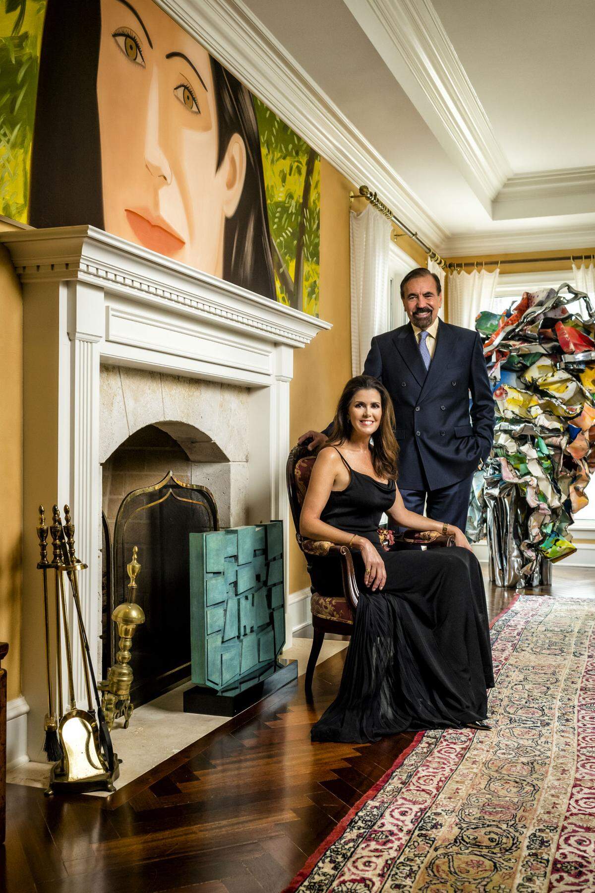 Darlene and Jorge Pérez in their living room, where a bronze Gunther Gerszo sculpture rests by the fireplace, and Alex Katz's 'Alba' hangs above the mantle. A John Chamberlain crushed auto parts sculpture dominates the far corner of the room. Photograph by Nick Garcia.