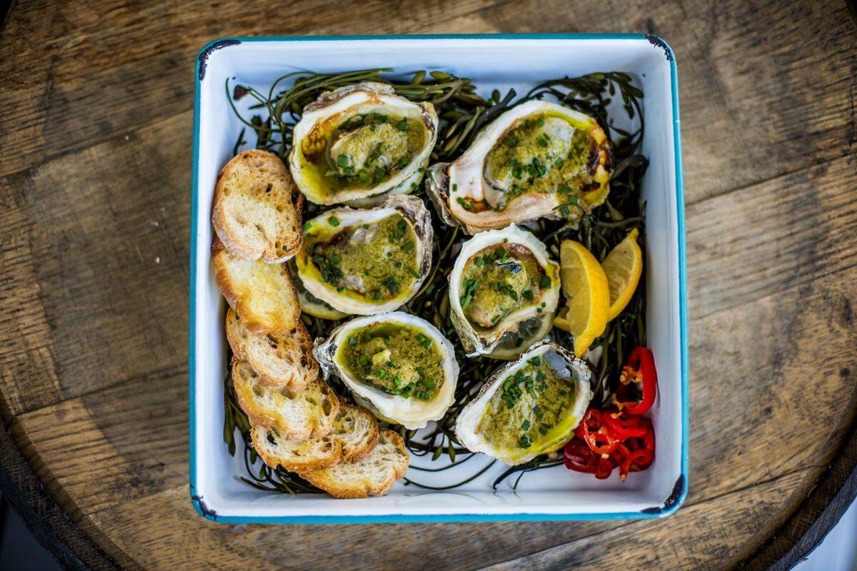 Wood-grilled oysters with herbed butter and sourdough at Stiltsville Fish Bar, by Chefs Janine Booth and Jeff McInnis. Photograph by Felipe Cuevas.