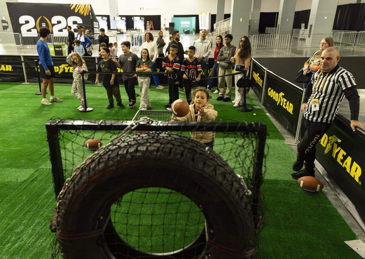 Kids wait in line to throw a football during the Playoff Fan Central at the Miami Beach Convention Center on Friday, Jan. 16, 2025, in Miami Beach, Fla. Fans can visit the event ahead of the College Football Playoff National Championship Game between the Miami Hurricanes and the Indiana Hoosiers and enjoy a variety of family-friendly interactive experiences.