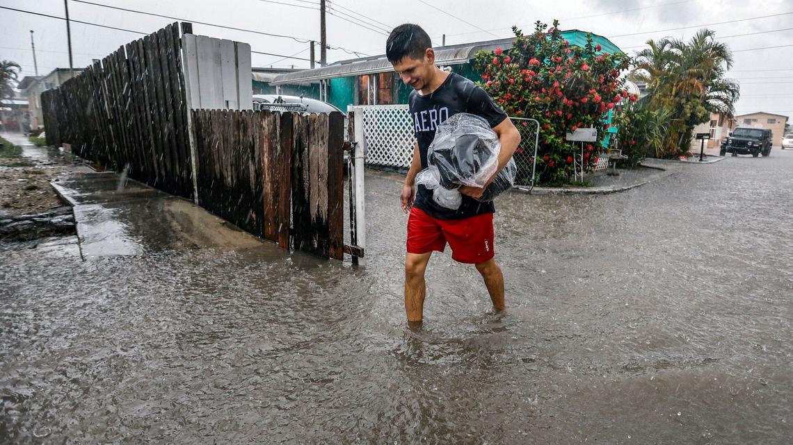 Davie Moreno walks through a flooded street at Holiday Acres Mobile Home Park in Hialeah, Florida on Wednesday, June 12, 2024.