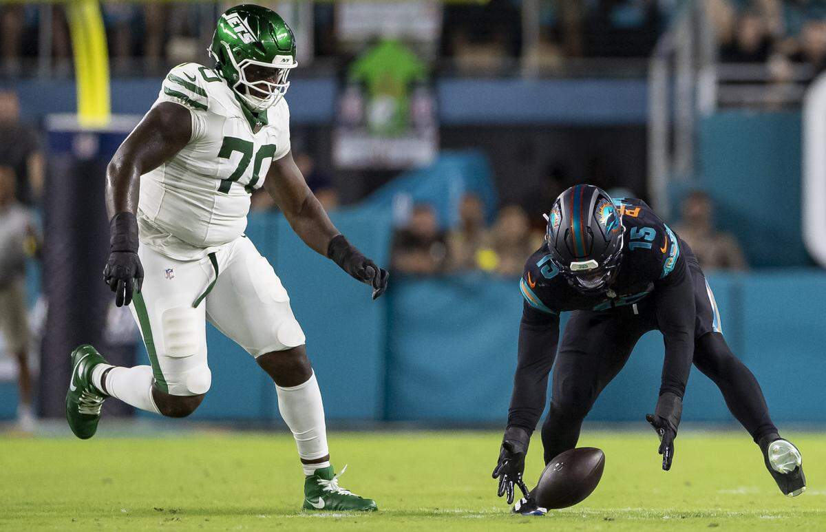 Miami Dolphins linebacker Jaelan Phillips (15) recovers a fumble as New York Jets offensive tackle Armand Membou (70) defends in the first half of their NFL game at Hard Rock Stadium on Monday, Sept. 29, 2025, in Miami Gardens, Fla.