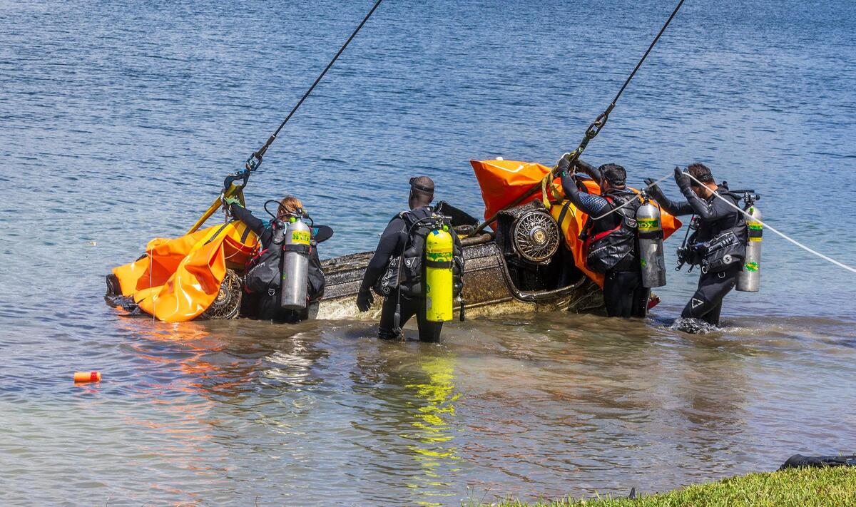 Buzos de la Policía y del Departamento de Bomberos de Miami-Dade se preparan para sacar un auto de un lago en Doral, el martes 8 de agosto de 2023. Los buzos localizaron unos 20 vehículos en el lago, siguiendo la pista de un equipo de buzos voluntarios que descubrió más de 30 autos en el lago cerca de Northwest 13th Terrace.