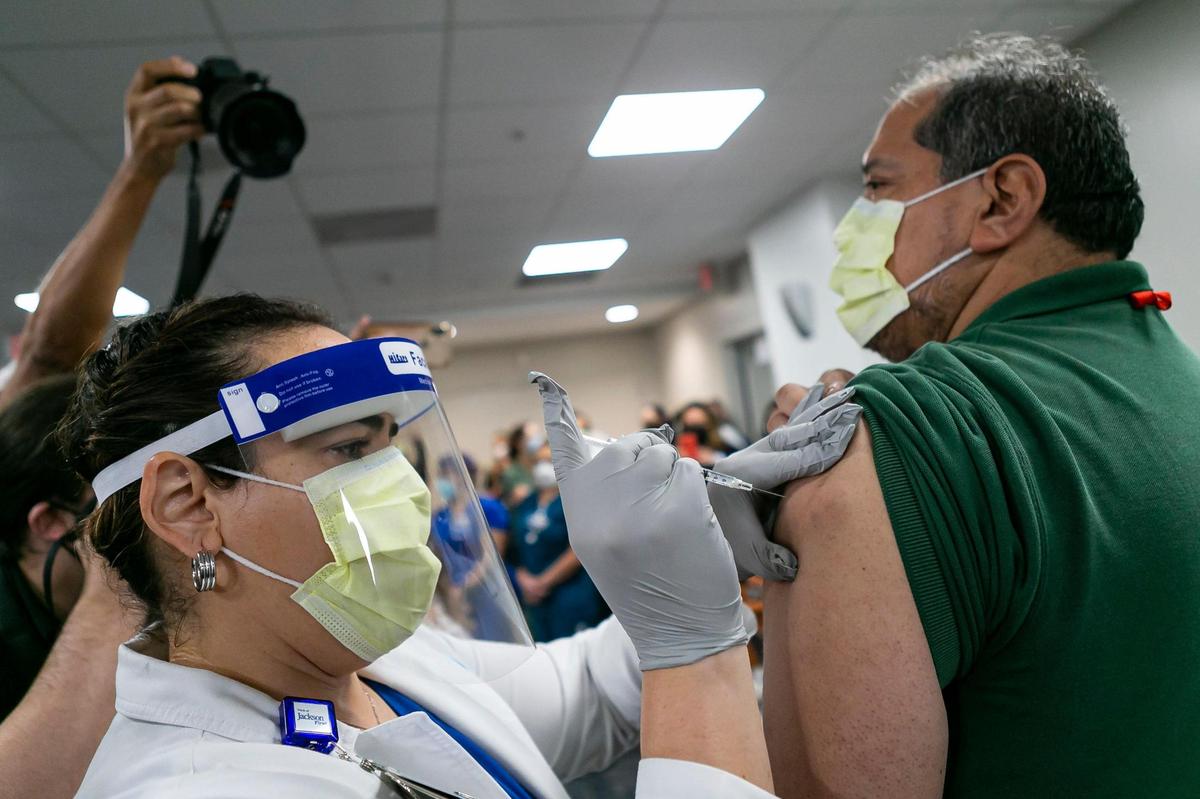 Environmental Service Worker Armando Acosta receives the Pfizer BioNTech COVID-19 vaccine at Jackson Memorial Hospital in Miami, Florida, on Tuesday, December 15, 2020.