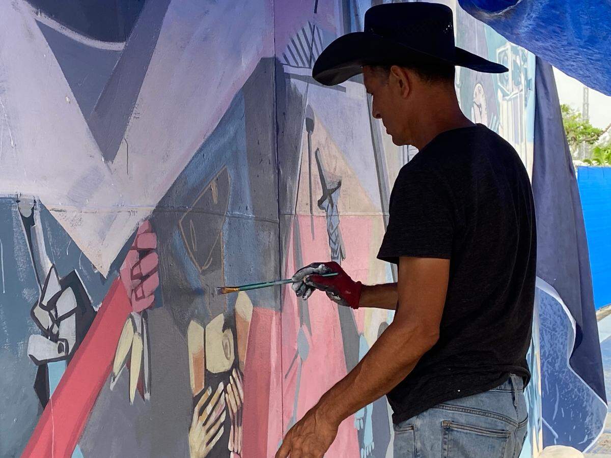 Artist Roberto Marquez paints on a mural at the memorial wall on Harding Avenue in Surfside, Florida, Saturday, July 10, 2021.