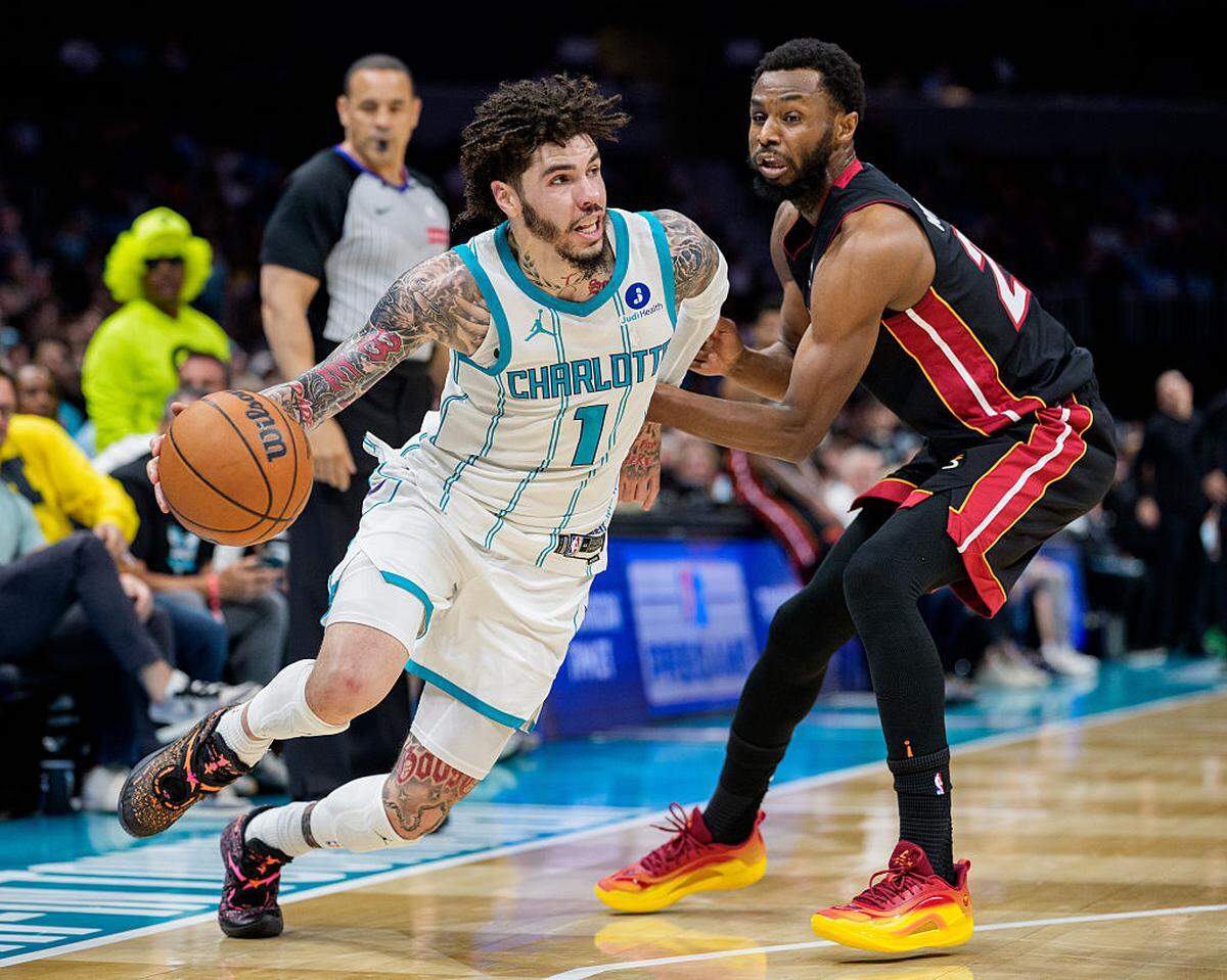 LaMelo Ball #1 of the Charlotte Hornets drives to the basket while guarded by Andrew Wiggins #22 of the Miami Heat in the first half during their game at Spectrum Center on April 14, 2026 in Charlotte, North Carolina.