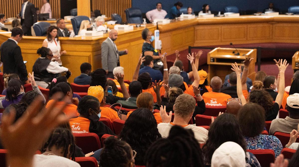 People wave their hands in support after a man who works with the homeless asks for more funds to help the homeless people in Miami during the first Miami-Dade county budget hearing on Thursday, Sept. 8, 2022, at the Stephen P. Clark Government Center in Downtown Miami. “We’re stretched thin,” he said.